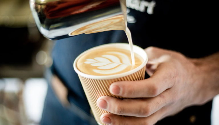 Barista hælder mælk i en cappuccino fra kaffevognen i Esbjerg